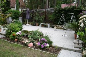 einen Garten mit einer Terrasse mit Blumen und einem Sonnenschirm in der Unterkunft Ferienhaus Klein in Dresden