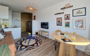 a living room with a table and a kitchen at L'Horizon doré, Vue mer et dunes, Plage à pied in Saint-Hilaire-de-Riez