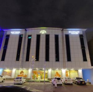 a large building with cars parked in a parking lot at Quiet Rooms 1 Serviced Apartments in Riyadh