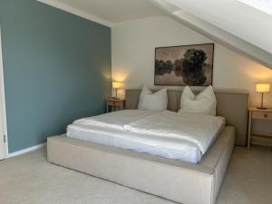 a bedroom with a bed with white sheets and pillows at Villa am Weinberg mit Garten großzügig und exklusiv in Geisenheim
