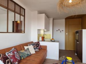 a living room with a brown couch and a kitchen at L'Horizon doré, Vue mer et dunes, Plage à pied in Saint-Hilaire-de-Riez +21 photos