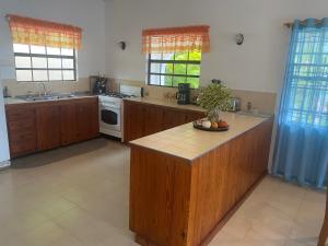 a large kitchen with wooden cabinets and a counter top at Immaculate 3 Bed Villa Overlooking Admiralty Bay in Union