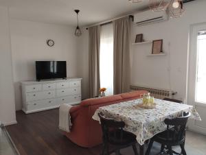 a living room with a red couch and a table at Apartmani Vidušin in Novalja