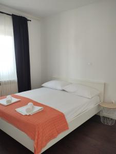 a white bed with two towels on top of it at Apartmani Vidušin in Novalja
