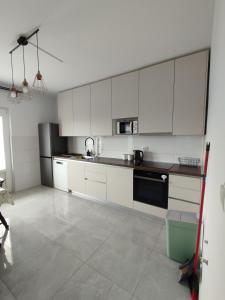 a kitchen with white cabinets and a black appliance at Apartmani Vidušin in Novalja