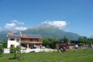 une maison avec des panneaux solaires sur son toit et une montagne dans l'établissement Agriturismo Al Bachero, à Belluno