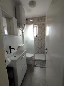 a white bathroom with a toilet and a sink at Apartmani Vidušin in Novalja
