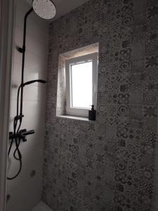 a bathroom with a shower and a window and a shower at Apartmani Vidušin in Novalja