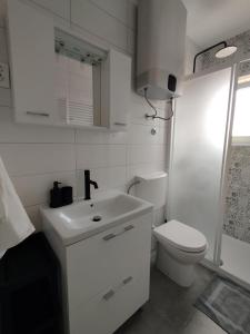 a white bathroom with a toilet and a sink at Apartmani Vidušin in Novalja