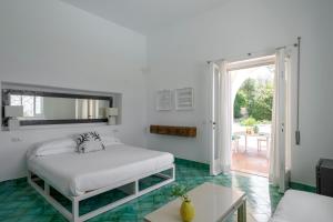 a white bedroom with a bed and a table at Il Carrubo Capri in Anacapri