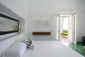 a white bedroom with a white bed and a window at Il Carrubo Capri in Anacapri
