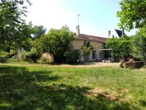 an old house with a grass yard in front of it at Grande maison de charme en pierre in Saint-Médard-de-Mussidan
