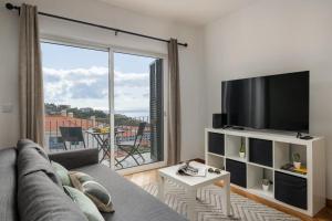 a living room with a couch and a flat screen tv at Alta Vista Caniço by An Island Apart in Santa Cruz
