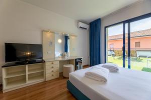 a bedroom with a bed and a tv and a window at Hi Hotels Riva del Garda in Riva del Garda
