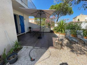 eine Terrasse mit einem Sonnenschirm, Stühlen und einem Tisch in der Unterkunft La Largatera in Frontignan