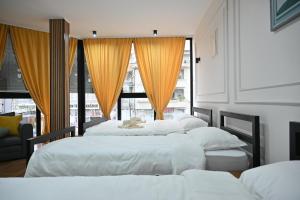 a group of three beds in a room with windows at Staša Apartmani in Novi Pazar