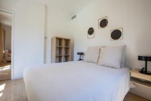 Un dormitorio blanco con una cama blanca y algunas fotos en la pared en Les Balcons de la Bourse, en Marsella 7 fotos más