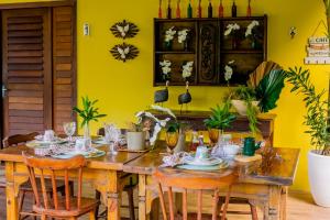 a dining room with a wooden table and yellow wall at Chalés serra linda in Bananeiras