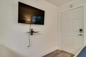 a flat screen tv hanging on a wall next to a door at Bright Gulf Coast Escape - 8 Mi to Johns Pass! in St Pete Beach