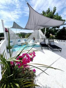 a patio with a white umbrella and some flowers at Nueva Vista INN in Cruz de Huanacaxtle