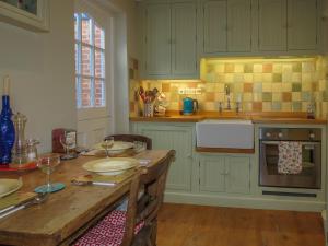 a kitchen with green cabinets and a wooden table at Ivy Cottage in Aldeburgh