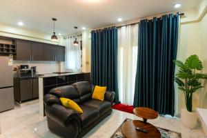 Una sala de estar con un sofá de cuero y una cocina. en Goshen Luxury Apartment C1, en Kampala
