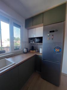 a kitchen with a refrigerator and a sink and a window at City Vibe Apartment in Tuzla