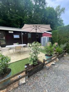 a backyard with a wooden deck with an umbrella at Cottage au calme Camping Les Tourterelles in La Celle-sous-Gouzon
