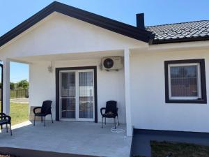 a white house with black chairs on a patio at Dream house in Laktaši