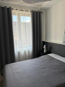 a bedroom with a bed and a window with curtains at Le nid de CALI in Pont-à-Mousson