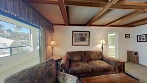 a living room with a leather couch and a large window at Comfortable Condo - Gorgeous Slopeview and Access to 3 Hot Tubs Unit 303 at 1849 in Mammoth Lakes