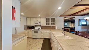 a large kitchen with white cabinets and a sink at Comfortable Condo - Gorgeous Slopeview and Access to 3 Hot Tubs Unit 303 at 1849 in Mammoth Lakes +35 photos