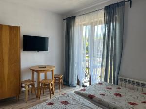 a hotel room with a bed and a table and a window at Willa Agma in Zakopane