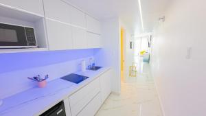 a white kitchen with a sink and a microwave at Water Side Studio King Bed With Pool in San Juan