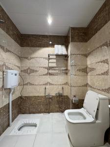 a bathroom with a toilet and a glass shower at فندق الملك - King Hotel in Karbalāʼ