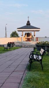 two benches in a park with a gazebo at Dom Pielgrzyma - Sanktuarium Matki Bożej Leśniańskiej in Leśna Podlaska