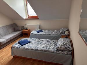 a room with three beds and a couch at Dom Pielgrzyma - Sanktuarium Matki Bożej Leśniańskiej in Leśna Podlaska