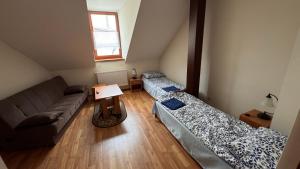 a living room with two beds and a couch at Dom Pielgrzyma - Sanktuarium Matki Bożej Leśniańskiej in Leśna Podlaska