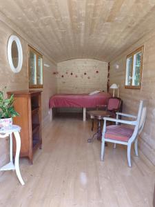 a room with a bed and a table and a chair at Roulotte au pied des volcans, cuisine et sdb de plein air in Orcines