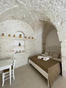 a bedroom with a bed and a table in a stone wall at L'hammam tra le volte a stella in Ceglie Messapica
