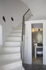 a staircase in a white room with a mirror at Elegant Santorini House 1 Bedroom Villa Windswept House Amazing Caldera View & Outdoor Hot Tub Oia in Thólos