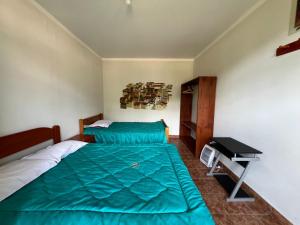 a bedroom with a bed with a green comforter and a desk at Mirador Lodge in Chacas
