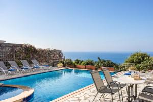 a pool with chairs and a table and the ocean at Lassi Seaview Villa Private Pool Villa Efrosini Short Walk To Resort Centre in Kefallonia