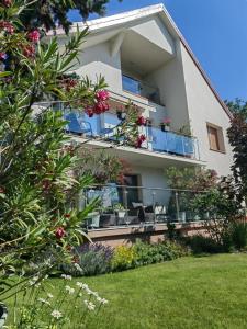a building with a balcony with flowers and plants at City Vendégház Balatonfüred in Balatonfüred
