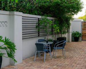 a patio with two chairs and a table against a wall at Arch Window garden apartment in Stellenbosch
