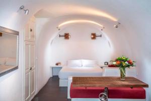 a bedroom with a bed and a table with a vase of flowers at Luxury Santorini Villa Full Moon Villa 1 Bedrooms Outdoor Plunge Pool Sea & Caldera View Oia in Thólos