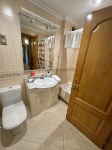 een badkamer met een toilet, een wastafel en een spiegel bij Apartamento Arnela Foz in Foz