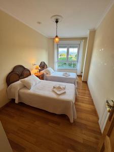 een slaapkamer met twee bedden en een raam bij Apartamento Arnela Foz in Foz