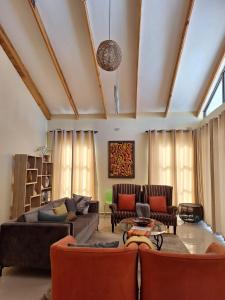 New, modern, airy luxurious 3 bed Home,Monavale Strathaven في هراري: غرفة معيشة مع أريكة وكراسي