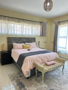 New, modern, airy luxurious 3 bed Home,Monavale Strathaven في هراري: غرفة نوم بسرير كبير عليها شراشف و وسائد وردية